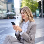 smiling-female-employee-suit-sitting-city-center-using-mobile-phone_1258-123397